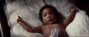 Movie still from “Ragtime” (1981), directed by Milos Forman – A baby laying on its back on a bed; Close Up shot, Overhead angle
