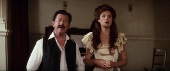 Movie still from “Ragtime” (1981), directed by Milos Forman – A man standing next to a woman in a room; Medium shot, Over the shoulder angle