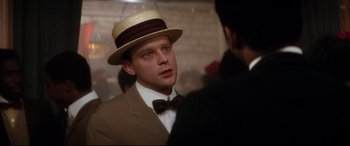 Movie still from “Ragtime” (1981), directed by Milos Forman – A man wearing a straw hat and a bow tie; Close Up shot, Over the shoulder angle