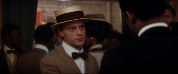 Movie still from “Ragtime” (1981), directed by Milos Forman – A man wearing a hat and a bow tie; Close Up shot, Over the shoulder angle
