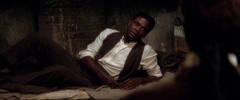 Movie still from “Ragtime” (1981), directed by Milos Forman – A man sitting on a bed wearing a vest; Medium shot, High angle