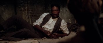Movie still from “Ragtime” (1981), directed by Milos Forman – A man sitting on a bed wearing a vest; Medium shot, High angle