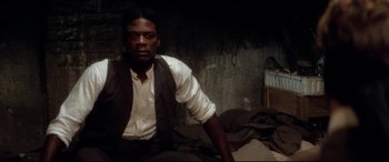 Movie still from “Ragtime” (1981), directed by Milos Forman – A man sitting on top of a bed in a room; Medium shot, High angle