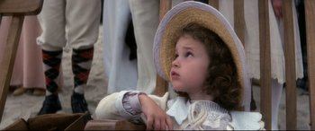 Movie still from “Ragtime” (1981), directed by Milos Forman – A little girl sitting in a chair wearing a straw hat; Close Up shot, High angle
