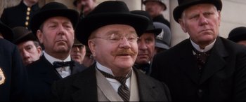 Movie still from “Ragtime” (1981), directed by Milos Forman – An old man with a mustache wearing a suit and a hat; Close Up shot, Low angle