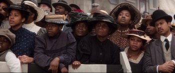 Movie still from “Ragtime” (1981), directed by Milos Forman – A group of people sitting in a crowd wearing hats; Medium shot, High angle