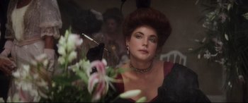 Movie still from “Ragtime” (1981), directed by Milos Forman – A person wearing a dress and holding a cigarette; Close Up shot, Over the shoulder angle