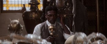 Movie still from “Ragtime” (1981), directed by Milos Forman – A man in a vest and tie holding a golden object; Close Up shot, High angle