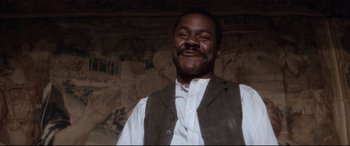 Movie still from “Ragtime” (1981), directed by Milos Forman – A man in a vest and tie smiling for the camera; Close Up shot, Low angle