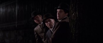 Movie still from “Ragtime” (1981), directed by Milos Forman – A group of men in suits and hats standing next to each other; Medium shot, Low angle