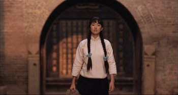 Movie still from “Raise the Red Lantern” (1991), directed by Yimou Zhang – A woman with long hair and a white shirt is walking; Medium shot, Low angle