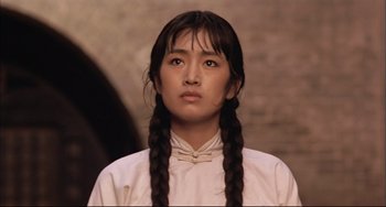 Movie still from “Raise the Red Lantern” (1991), directed by Yimou Zhang – A young woman with long braids wearing a white shirt; Close Up shot, Low angle