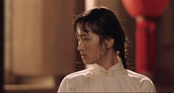 Movie still from “Raise the Red Lantern” (1991), directed by Yimou Zhang – A young woman with long black hair wearing a white shirt; Close Up shot, Low angle