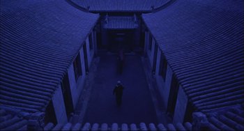 Movie still from “Raise the Red Lantern” (1991), directed by Yimou Zhang – A person walking down a street at night; Extreme Wide shot, High angle