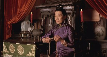 Movie still from “Raise the Red Lantern” (1991), directed by Yimou Zhang – A woman in a purple dress holding a string of beads; Medium shot, Low angle