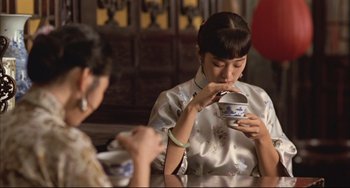 Movie still from “Raise the Red Lantern” (1991), directed by Yimou Zhang – Two women sitting at a table with a cup of tea; Medium shot, Over the shoulder angle