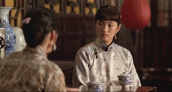 Movie still from “Raise the Red Lantern” (1991), directed by Yimou Zhang – Two women are sitting at a table with tea cups in front of them; Close Up shot, Over the shoulder angle