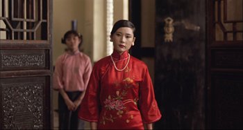 Movie still from “Raise the Red Lantern” (1991), directed by Yimou Zhang – A woman in a red dress standing next to another woman in a pink dress; Medium shot, Over the shoulder angle