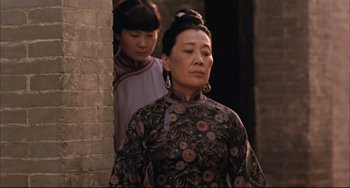 Movie still from “Raise the Red Lantern” (1991), directed by Yimou Zhang – A woman standing next to another woman in a doorway; Medium shot, Low angle