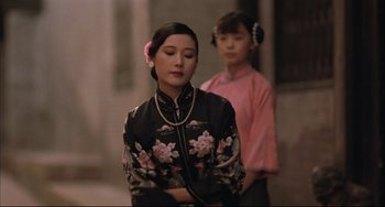 Movie still from “Raise the Red Lantern” (1991), directed by Yimou Zhang – A woman in a floral dress and a girl in a pink dress; Medium shot, Over the shoulder angle
