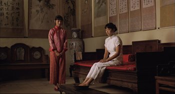 Movie still from “Raise the Red Lantern” (1991), directed by Yimou Zhang – Two women sitting on a bench in a room; Wide shot, Low angle