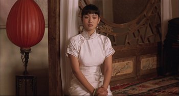 Movie still from “Raise the Red Lantern” (1991), directed by Yimou Zhang – A woman in a white dress sitting on the ground; Medium shot, Over the shoulder angle