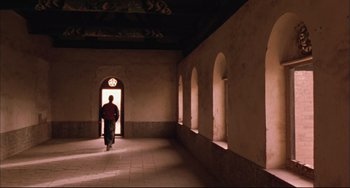 Movie still from “Raise the Red Lantern” (1991), directed by Yimou Zhang – A man walking in a hallway with a light shining on him; Wide shot, Low angle