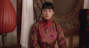 Movie still from “Raise the Red Lantern” (1991), directed by Yimou Zhang – A woman in a red and gold dress is posing for a picture; Close Up shot, Over the shoulder angle