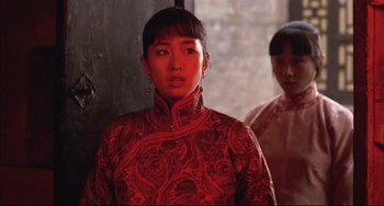 Movie still from “Raise the Red Lantern” (1991), directed by Yimou Zhang – A woman in a red dress standing next to another woman; Medium shot, Over the shoulder angle