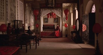 Movie still from “Raise the Red Lantern” (1991), directed by Yimou Zhang – Two people sitting on a bed inside of a room; Wide shot, High angle