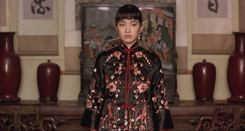 Movie still from “Raise the Red Lantern” (1991), directed by Yimou Zhang – A woman in a black and red dress standing in front of a painting; Medium shot, Low angle