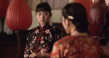 Movie still from “Raise the Red Lantern” (1991), directed by Yimou Zhang – A woman in a red and black dress looking in the mirror; Close Up shot, Over the shoulder angle