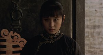 Movie still from “Raise the Red Lantern” (1991), directed by Yimou Zhang – A young asian woman wearing a black dress; Close Up shot, Over the shoulder angle