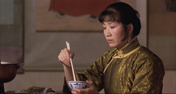 Movie still from “Raise the Red Lantern” (1991), directed by Yimou Zhang – A woman holding chopsticks while holding a bowl of food; Close Up shot, Low angle