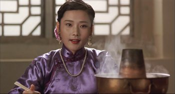Movie still from “Raise the Red Lantern” (1991), directed by Yimou Zhang – A woman in a purple dress is standing in front of a pot of water; Close Up shot, Low angle