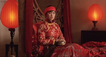 Movie still from “Raise the Red Lantern” (1991), directed by Yimou Zhang – A woman sitting on a chair wearing a red dress; Medium shot, Low angle