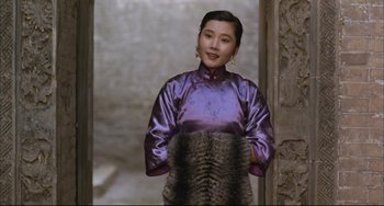 Movie still from “Raise the Red Lantern” (1991), directed by Yimou Zhang – A woman in a purple dress standing in front of a stone wall; Medium shot, Low angle