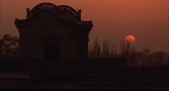 Movie still from “Raise the Red Lantern” (1991), directed by Yimou Zhang – The sun is setting behind a building with a bird perched on it; Extreme Wide shot, Low angle