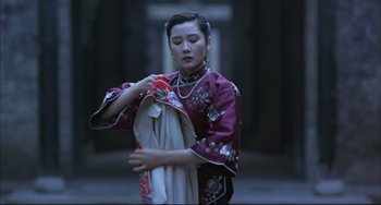 Movie still from “Raise the Red Lantern” (1991), directed by Yimou Zhang – A woman in a red and white dress holding a towel; Medium shot, Low angle