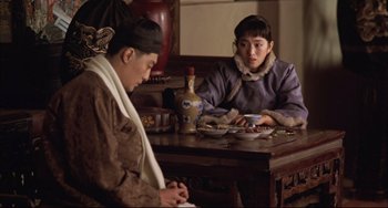 Movie still from “Raise the Red Lantern” (1991), directed by Yimou Zhang – A man and a woman sitting at a dining table; Medium shot, Over the shoulder angle