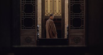 Movie still from “Raise the Red Lantern” (1991), directed by Yimou Zhang – A man standing in front of an open door; Wide shot, Low angle