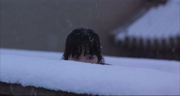 Movie still from “Raise the Red Lantern” (1991), directed by Yimou Zhang – A woman is peeking out from the snow covered ground; Medium shot, Low angle