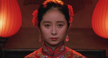 Movie still from “Raise the Red Lantern” (1991), directed by Yimou Zhang – A woman in a red dress with red flowers in her hair; Close Up shot, Over the shoulder angle