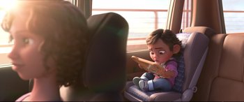 Movie still from “Ralph Breaks the Internet” (2018), directed by Rich Moore – A little girl sitting in a car seat looking at a book; Medium shot, Over the shoulder angle