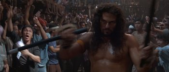 Movie still from “Rambo III” (1988), directed by Peter MacDonald – A man with long curly hair holding a baseball bat; Medium shot, Low angle