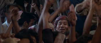 Movie still from “Rambo III” (1988), directed by Peter MacDonald – A group of people sitting in a room with their hands raised; Medium shot, High angle