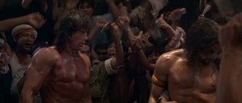 Movie still from “Rambo III” (1988), directed by Peter MacDonald – A group of people in a room with arms raised; Medium shot, Low angle