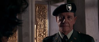 Movie still from “Rambo III” (1988), directed by Peter MacDonald – An older man in a military uniform is standing in front of a door; Close Up shot, Over the shoulder angle