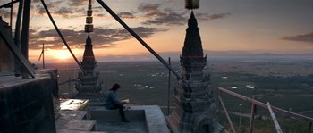 Movie still from “Rambo III” (1988), directed by Peter MacDonald – A woman sitting on a ledge looking at the sky; Extreme Wide shot, Low angle