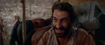 Movie still from “Rambo III” (1988), directed by Peter MacDonald – A man with a beard smiling for the camera; Close Up shot, Over the shoulder angle